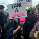 boy holding I am a feminst protest sign