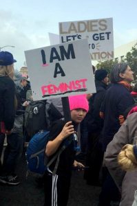 boy holding I am a feminst protest sign