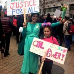 Woman dressed as Statue of Liberty with girl holding Girl Power sign