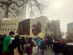 Downtown Oakland mural with Womens March in background