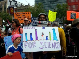 Dude in an astronaut helmit's sign: [fists up] "Defiance for science"